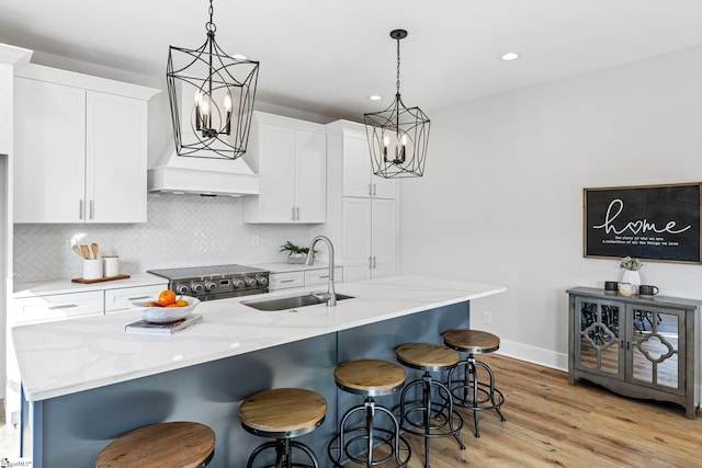 kitchen featuring stainless steel range, white cabinets, sink, and light hardwood / wood-style floors