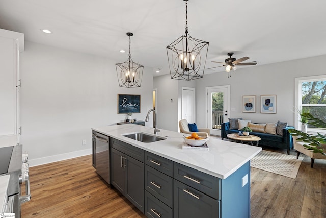 kitchen with plenty of natural light, stainless steel dishwasher, sink, and an island with sink