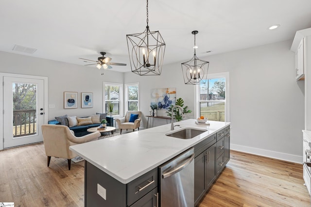 kitchen with sink, dishwasher, light wood-type flooring, pendant lighting, and a center island with sink