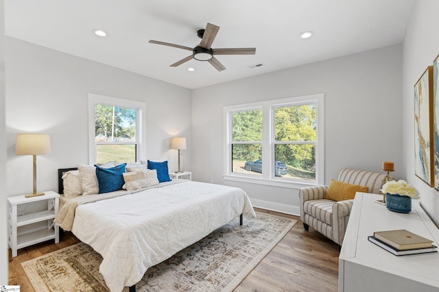 bedroom featuring multiple windows, light hardwood / wood-style floors, and ceiling fan