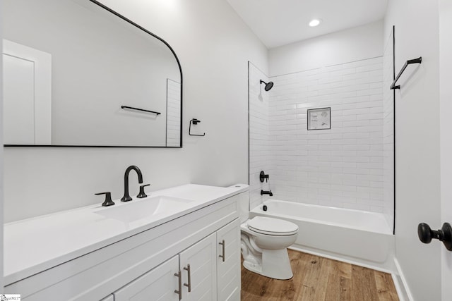 full bathroom featuring vanity, tiled shower / bath combo, wood-type flooring, and toilet