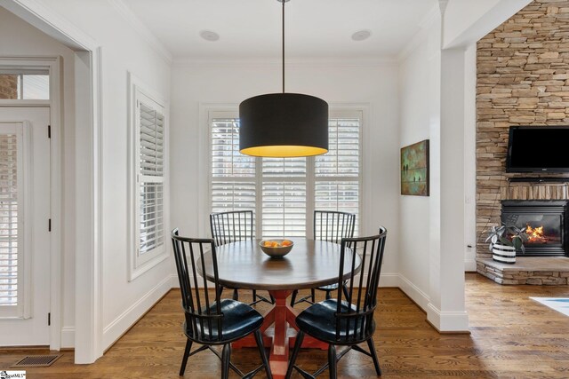 dining room with ornamental molding, hardwood / wood-style floors, and a fireplace