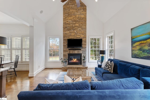 living room with light hardwood / wood-style floors, high vaulted ceiling, a fireplace, and ceiling fan