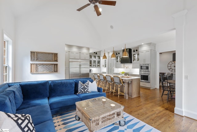 living room featuring dark wood-type flooring, ceiling fan, and high vaulted ceiling