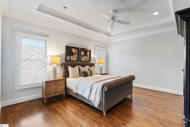 bedroom featuring ceiling fan, a tray ceiling, ornamental molding, and dark hardwood / wood-style flooring