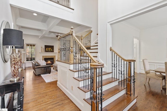 stairway featuring beamed ceiling, hardwood / wood-style floors, crown molding, and coffered ceiling