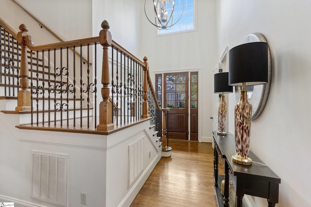 entrance foyer featuring hardwood / wood-style floors, a notable chandelier, and a towering ceiling