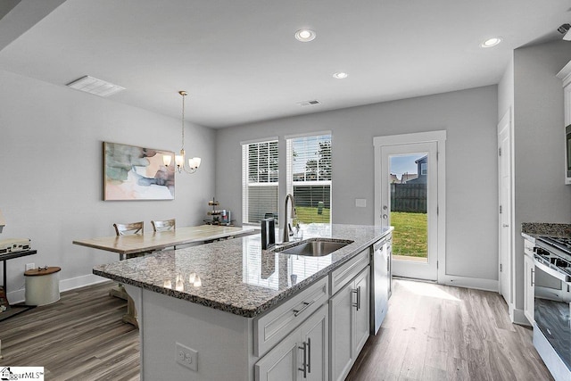 kitchen featuring a kitchen island with sink, a healthy amount of sunlight, sink, and dark hardwood / wood-style flooring