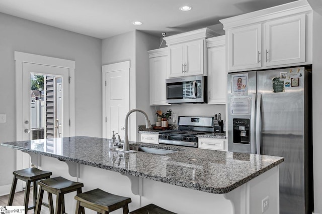 kitchen with white cabinets, dark hardwood / wood-style flooring, a kitchen island with sink, sink, and stainless steel appliances