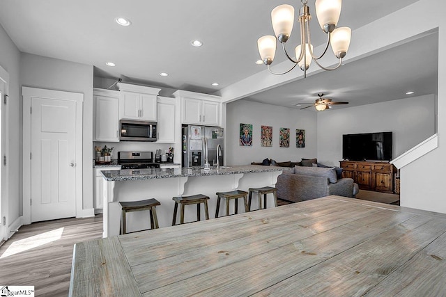 dining area featuring light wood-type flooring and ceiling fan with notable chandelier