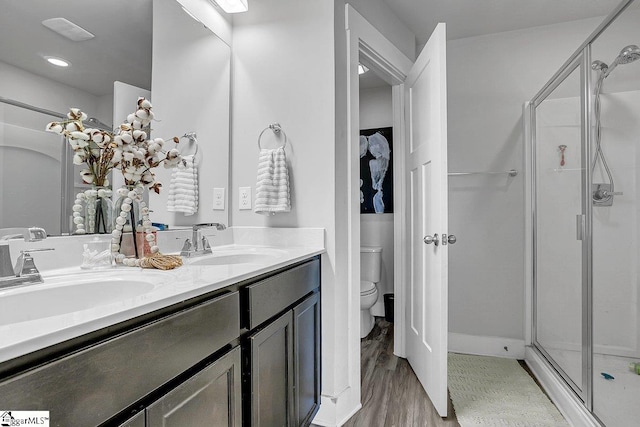 bathroom featuring a shower with door, vanity, hardwood / wood-style flooring, and toilet