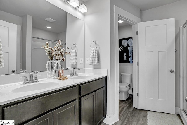 bathroom with toilet, an enclosed shower, vanity, and wood-type flooring