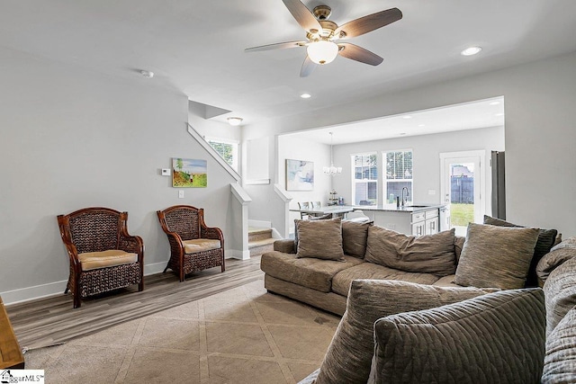 living room featuring sink, ceiling fan with notable chandelier, and light wood-type flooring