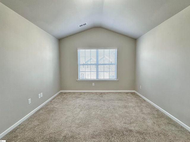 carpeted empty room featuring lofted ceiling