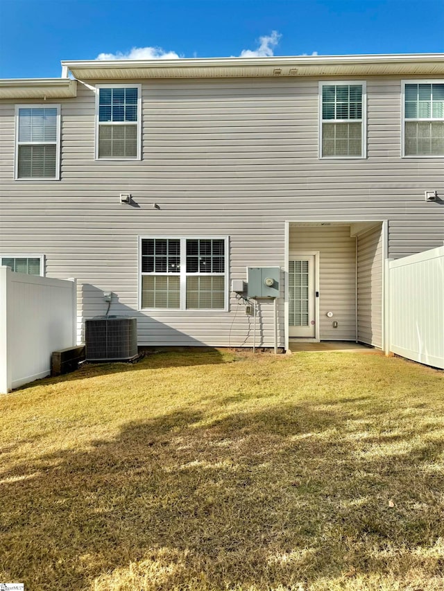 rear view of house featuring central air condition unit and a yard