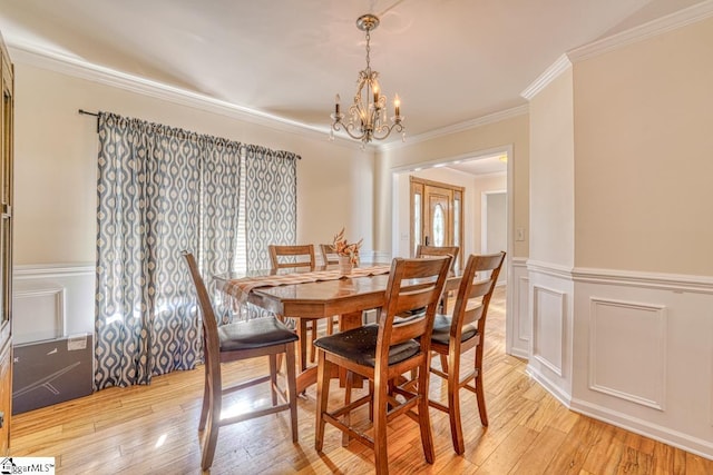 dining space with light hardwood / wood-style flooring, ornamental molding, and a notable chandelier