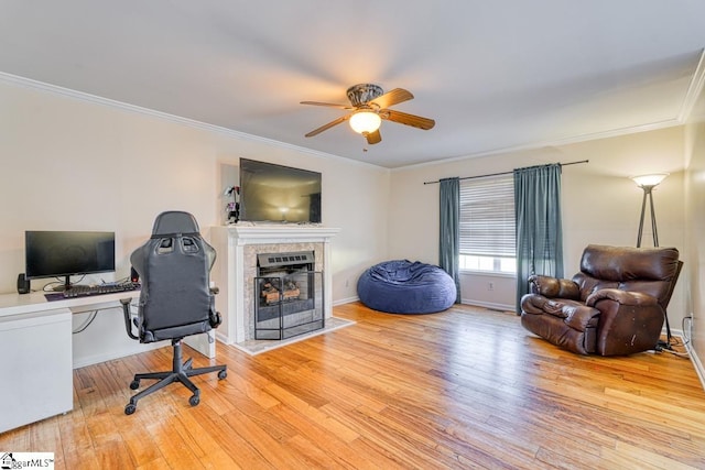 office space with ornamental molding, light hardwood / wood-style flooring, a tiled fireplace, and ceiling fan