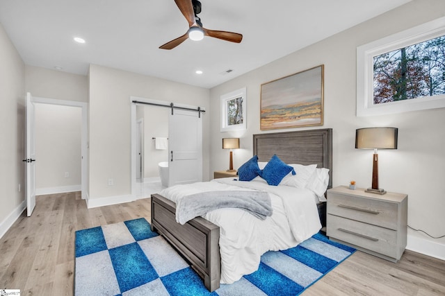 bedroom with recessed lighting, baseboards, a barn door, and light wood-style flooring