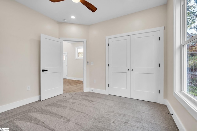 unfurnished bedroom with light carpet, a closet, and ceiling fan