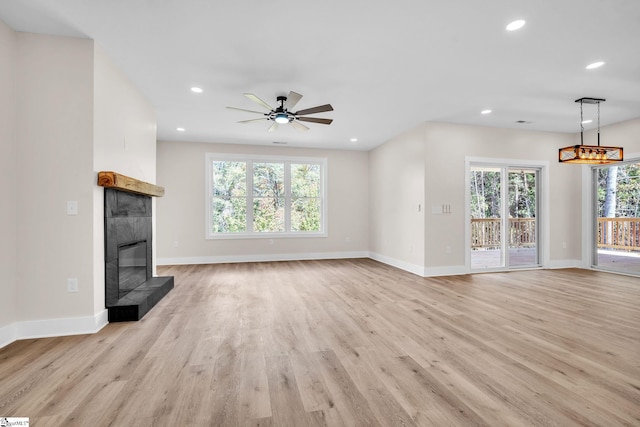 unfurnished living room featuring light hardwood / wood-style flooring, a tiled fireplace, and ceiling fan