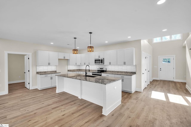 kitchen featuring an island with sink, stainless steel appliances, and white cabinetry