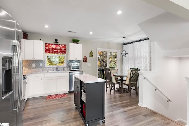 kitchen featuring white cabinetry, stainless steel appliances, light hardwood / wood-style flooring, and a kitchen island