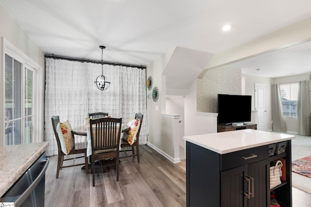 kitchen featuring dishwasher, light wood-type flooring, a center island, hanging light fixtures, and a notable chandelier