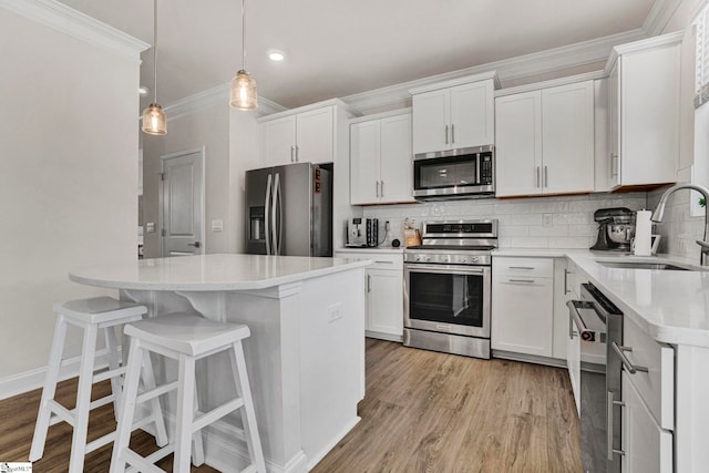 kitchen featuring appliances with stainless steel finishes, light hardwood / wood-style flooring, white cabinetry, and sink