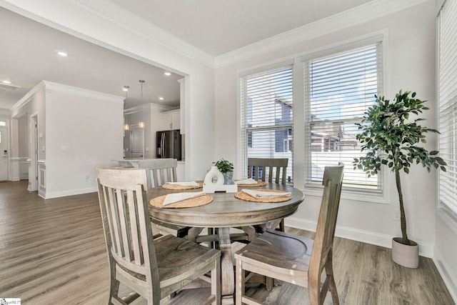 dining area with a wealth of natural light, ornamental molding, and hardwood / wood-style floors