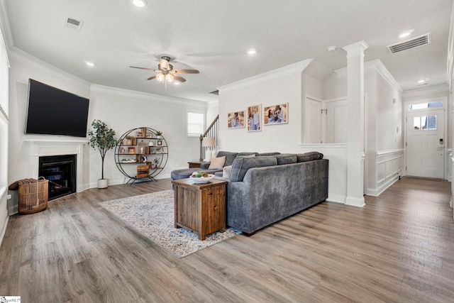 living room with crown molding, decorative columns, light hardwood / wood-style flooring, and ceiling fan