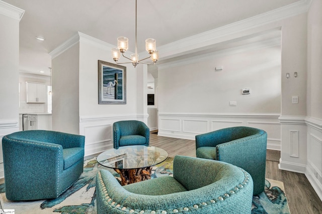 sitting room with ornamental molding, wood-type flooring, and an inviting chandelier