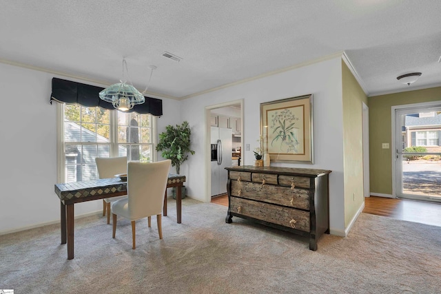 carpeted dining space with ornamental molding and a textured ceiling