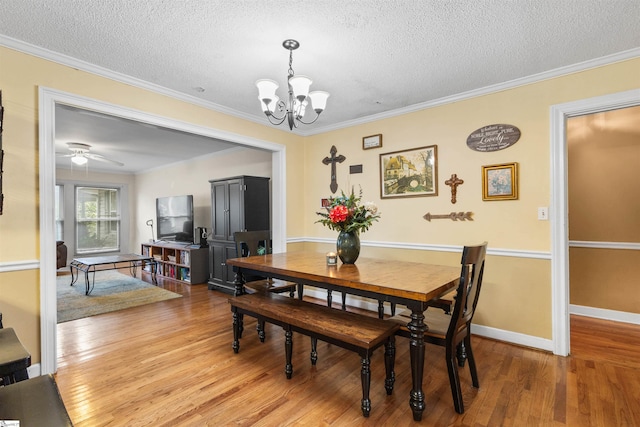 dining area featuring ornamental molding, a textured ceiling, hardwood / wood-style flooring, and ceiling fan with notable chandelier