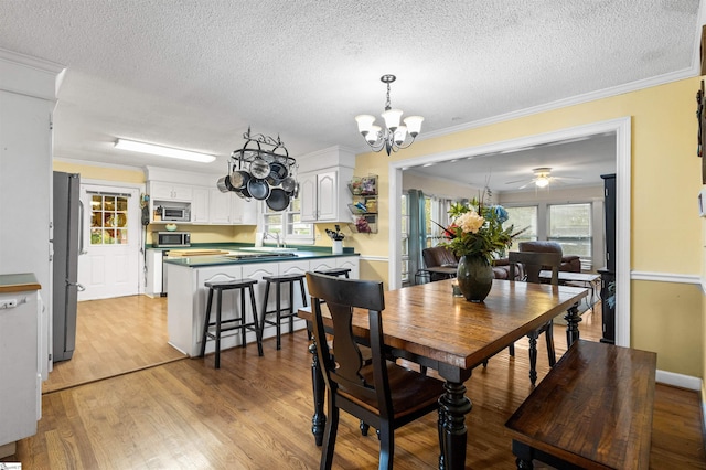 dining area with light wood-type flooring, ornamental molding, and plenty of natural light