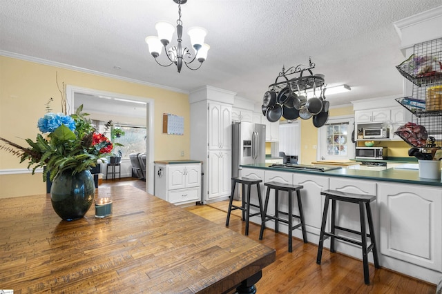 dining room featuring an inviting chandelier, crown molding, a textured ceiling, and light hardwood / wood-style floors