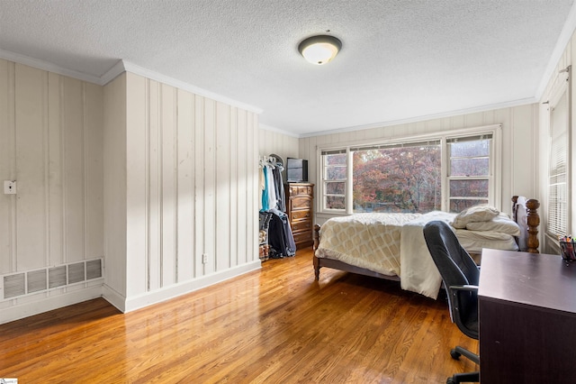 bedroom with crown molding, hardwood / wood-style floors, and a textured ceiling