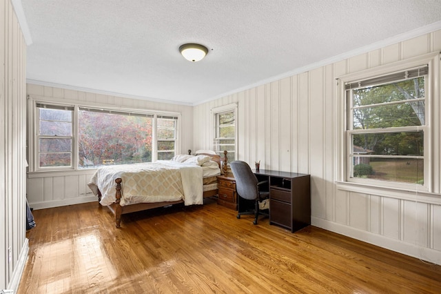 bedroom featuring ornamental molding, multiple windows, and light wood-type flooring