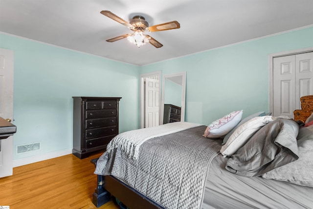 bedroom with a closet, ceiling fan, hardwood / wood-style flooring, and crown molding