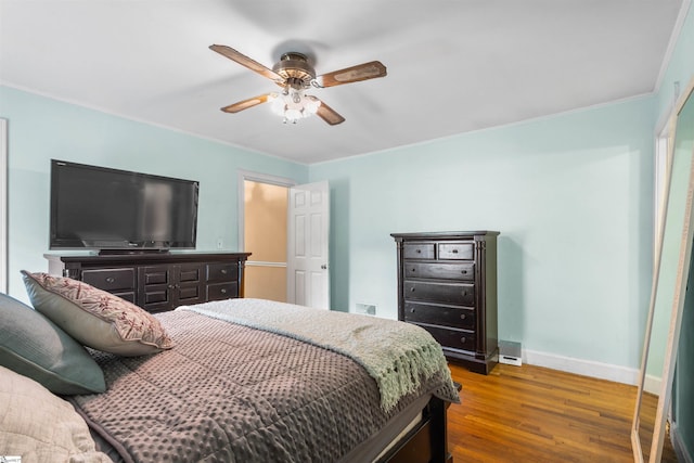 bedroom with crown molding, dark hardwood / wood-style floors, and ceiling fan