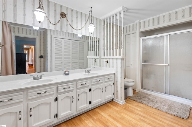 bathroom with hardwood / wood-style floors, a shower with door, toilet, ornamental molding, and vanity