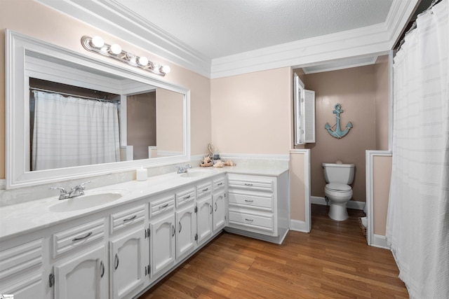 bathroom featuring a textured ceiling, hardwood / wood-style floors, toilet, vanity, and crown molding