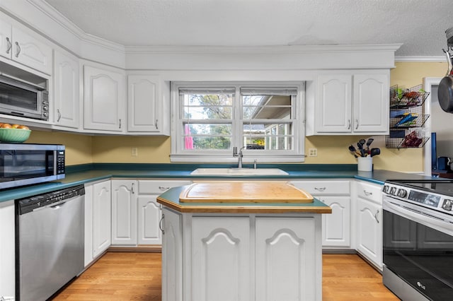 kitchen with light hardwood / wood-style flooring, a center island, white cabinets, and stainless steel appliances