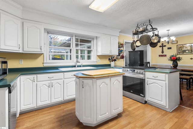 kitchen featuring stainless steel appliances, sink, a center island, an inviting chandelier, and white cabinets