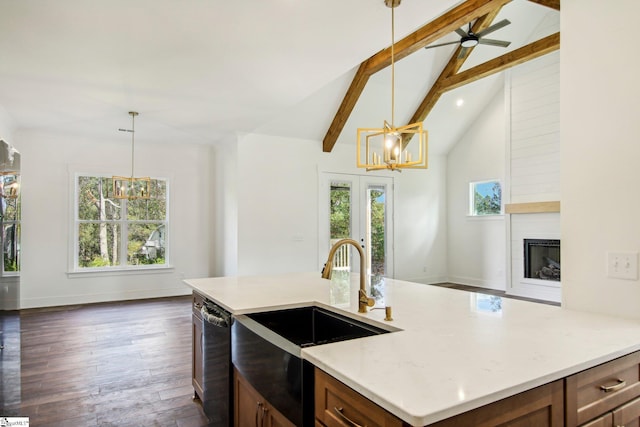 kitchen with black dishwasher, sink, a fireplace, pendant lighting, and dark wood-type flooring