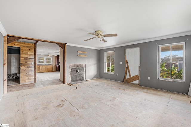 unfurnished living room with crown molding, ceiling fan, and plenty of natural light