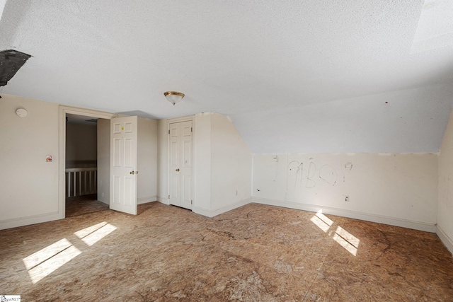 additional living space featuring lofted ceiling and a textured ceiling