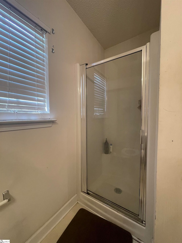 bathroom with a shower with door and a textured ceiling