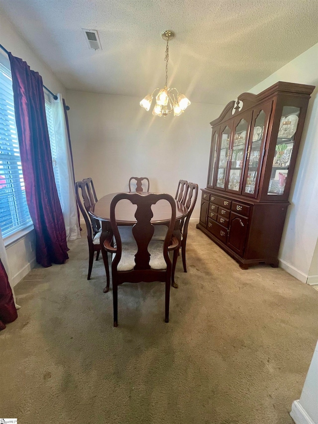 unfurnished dining area with light carpet, an inviting chandelier, a textured ceiling, and a wealth of natural light