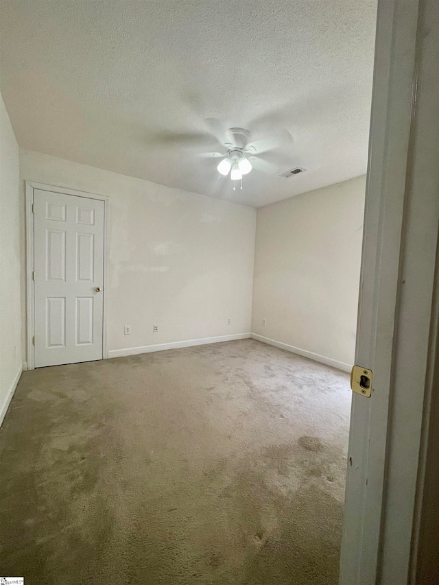 empty room with carpet floors, a textured ceiling, and ceiling fan