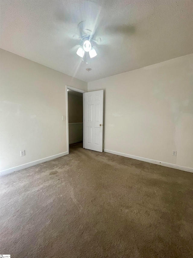 unfurnished room featuring a textured ceiling, carpet flooring, and ceiling fan